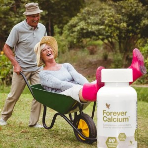 Seniors souriants avec une boite de comprimés de Forever Calcium, symbolisant la santé osseuse chez les personnes âgées.