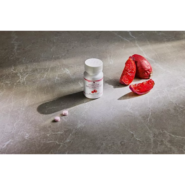 Gros plan sur le flacon de Forever Absorbent-D et les comprimés à mâcher avec des figues coupées sur une surface grise moderne.