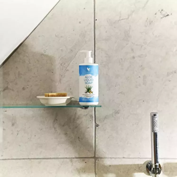 Forever Aloe Liquid Soap posé sur une étagère de salle de bain avec une brosse et un décor moderne.