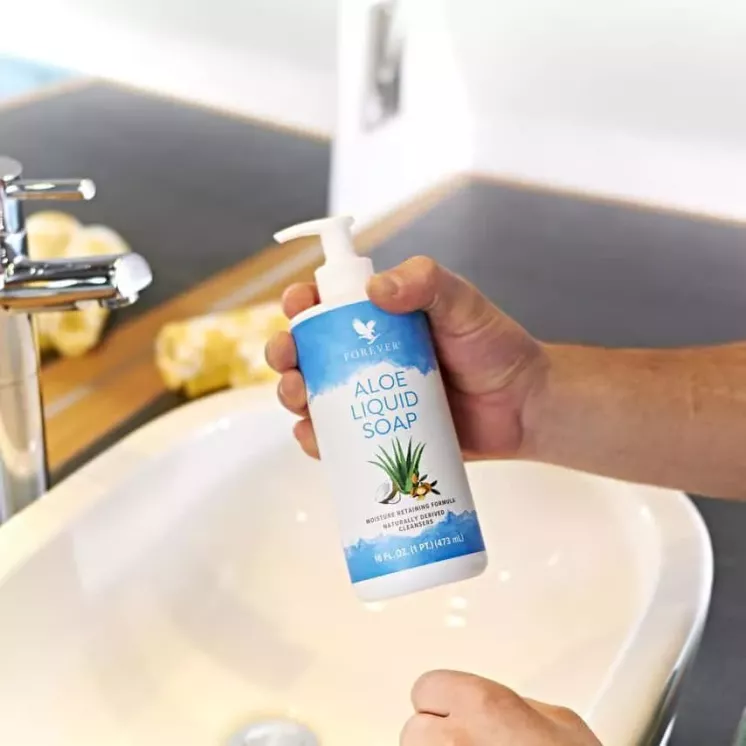Homme tenant une bouteille de Forever Aloe Liquid Soap au-dessus d’un lavabo pour l’utiliser.
