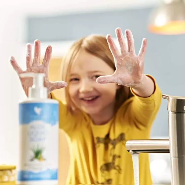 Enfant souriant et montrant ses mains recouvertes de mousse après l’utilisation de Forever Aloe Liquid Soap.