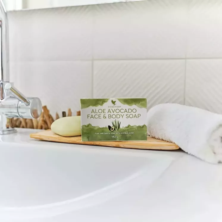 Savon Aloe Avocado Face & Body Soap posé sur un évier, accompagné d’une serviette blanche, parfait pour le visage et le corps.