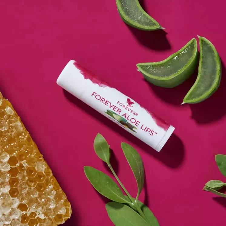 Stick Forever Aloe Lips posé sur fond rose avec Aloe Vera, cire d’abeille et feuilles de jojoba. Ingrédients naturels.