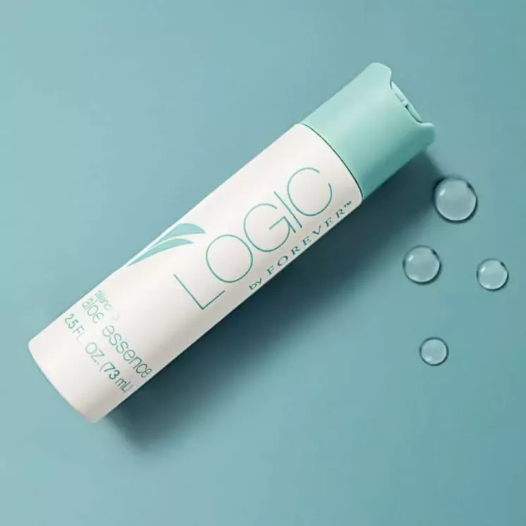 Flacon couché de l’Essence Tonifiante Logic by Forever sur fond bleu avec gouttes d’eau