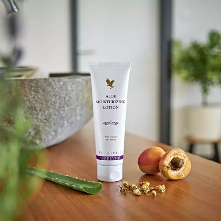 Crème Aloe Moisturizing Lotion Forever posée sur une table en bois avec aloe vera, abricots et camomille en arrière-plan