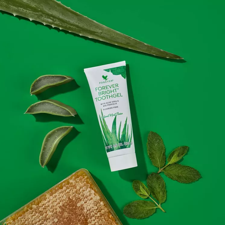 Dentifrice aloe vera avec feuilles d'aloe et propolis composition visuelle sur fond vert