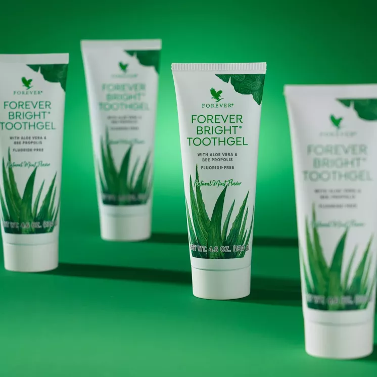 Plusieurs tubes Forever Bright Toothgel dentifrice aloe vera sur fond vert effet gamme