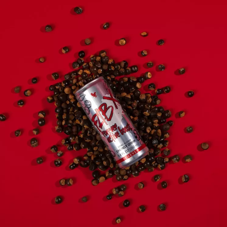 Canette FAB X entourée de graines de guarana sur fond rouge