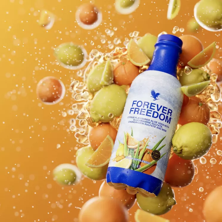 Bouteille de Forever Freedom entourée d’agrumes sur fond orange