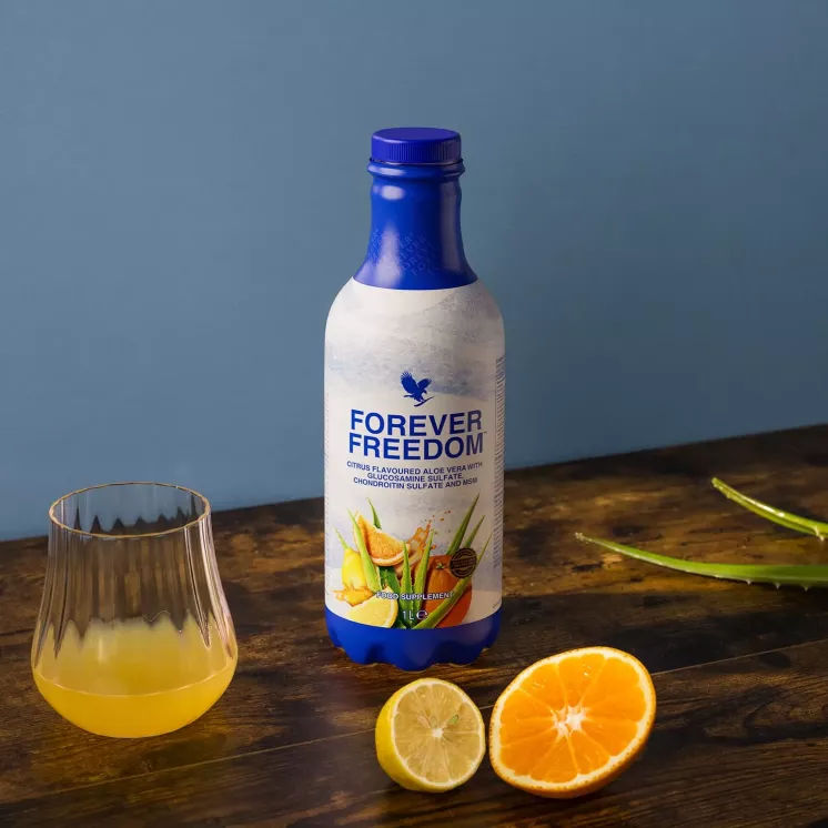 Bouteille et verre de Forever Freedom avec orange, citron et feuilles d’aloe vera