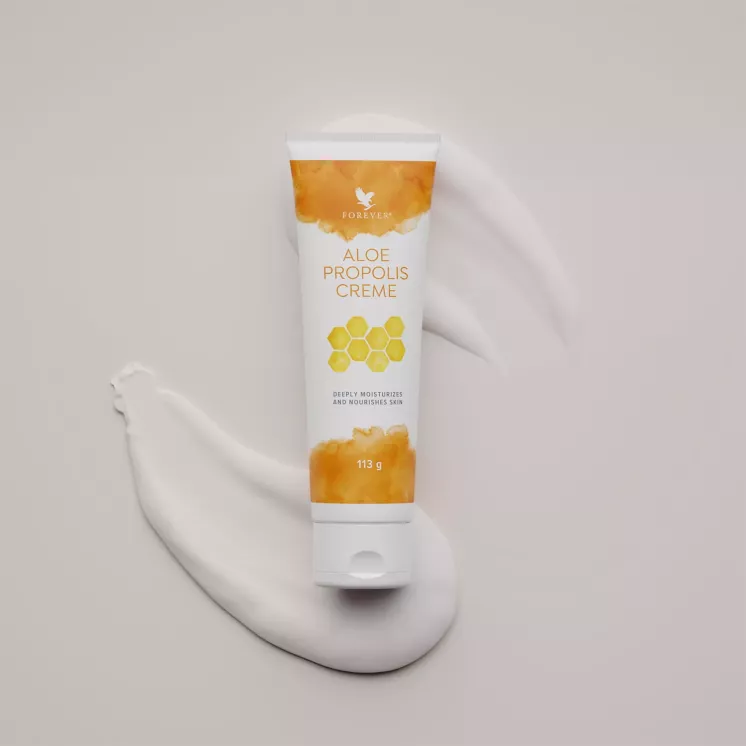 Tube Aloe Propolis Crème avec une traînée de crème blanche en arrière-plan.