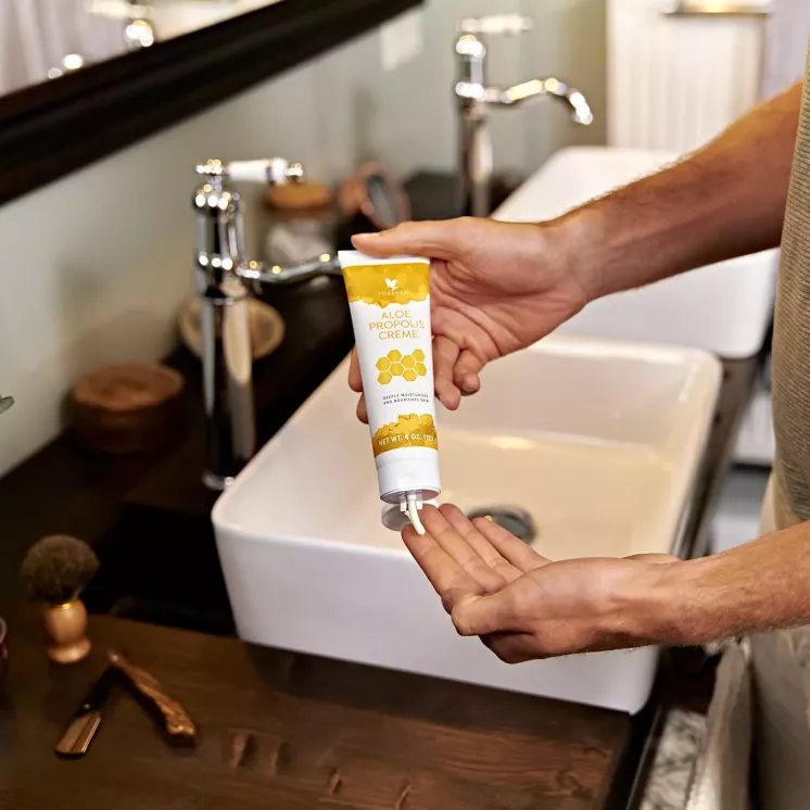 Crème déposée dans la paume depuis un tube Aloe Propolis Crème ouvert.